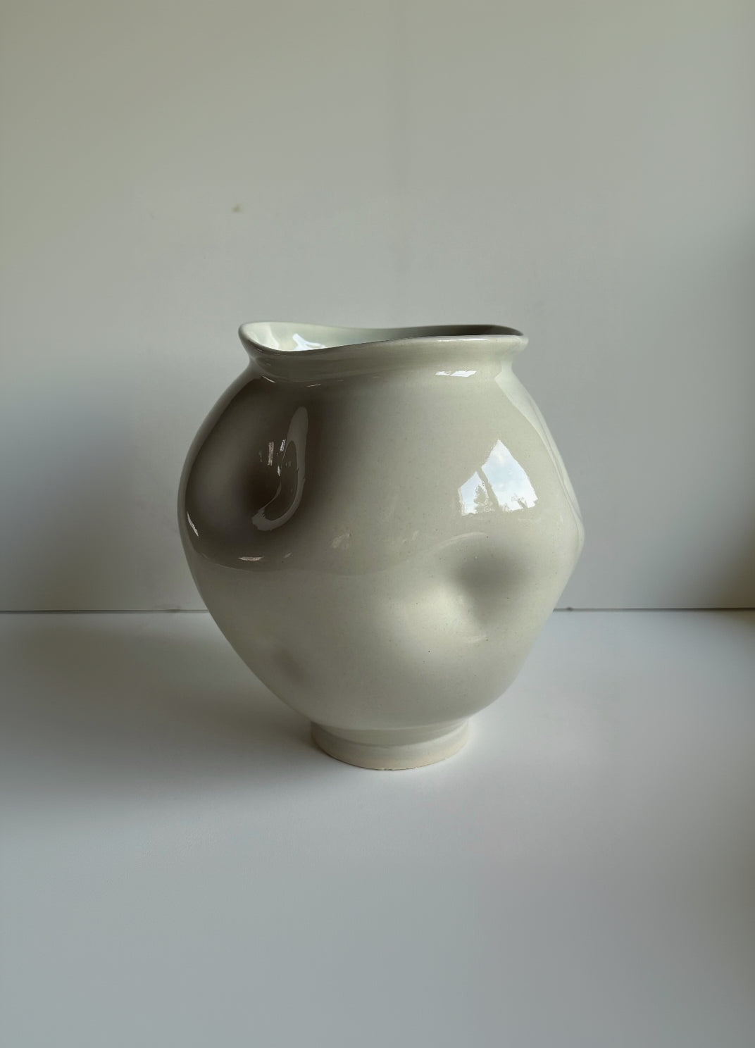 Light green, ceramic moon jar with large dimples. on a white background
